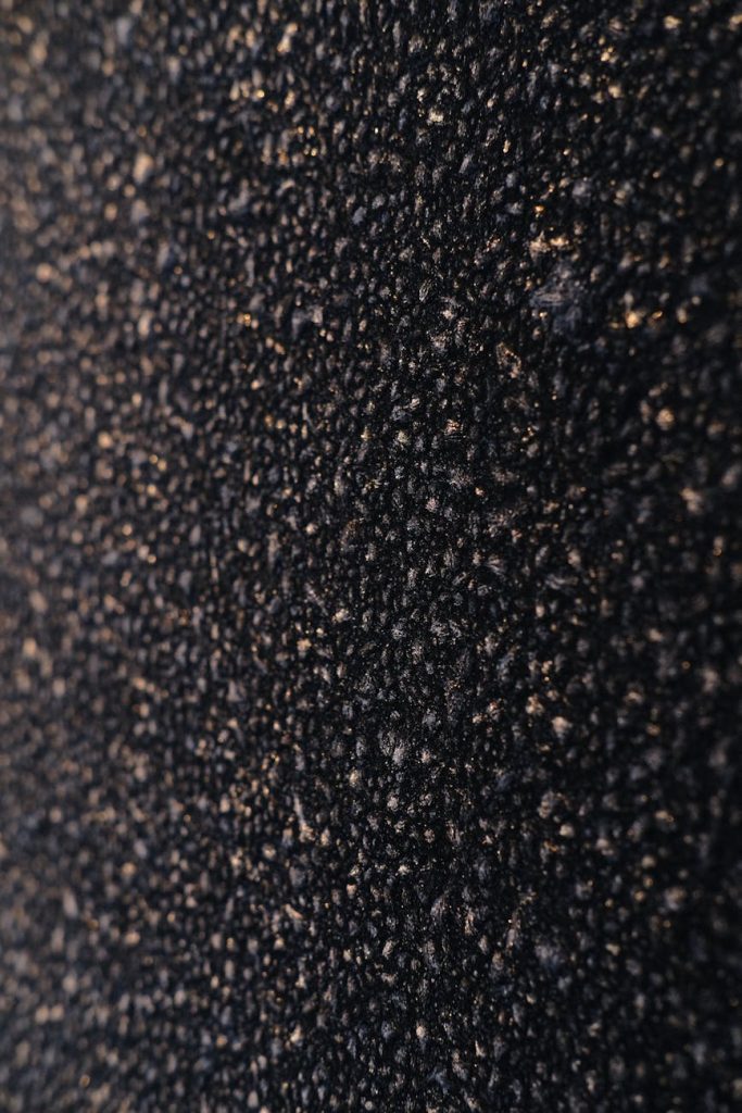 Detailed close-up of rough black asphalt texture, perfect for background or design projects.