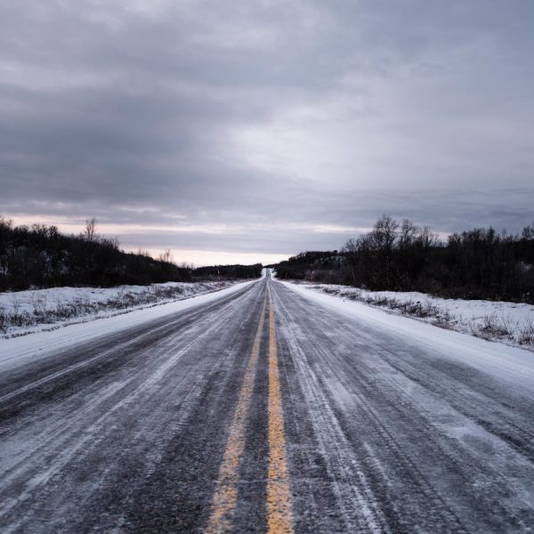 A lonely snow-covered road under a cloudy sky in winter.