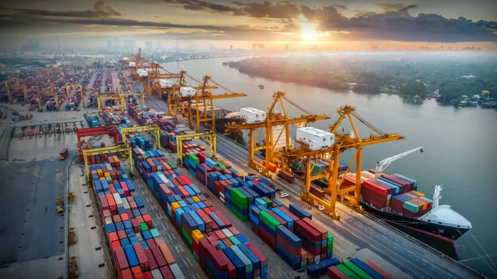 Large cargo container ship docked at a busy port, representing global freight options for chemical exports.