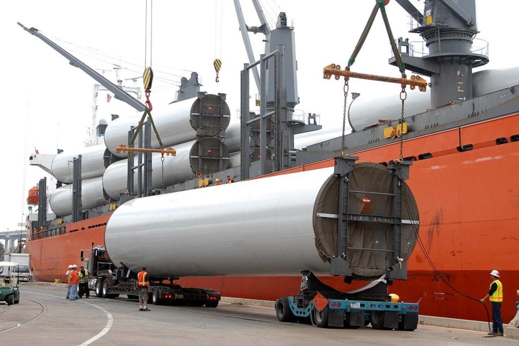 A large bulk chemical tanker being loaded with cargo at a busy industrial port.