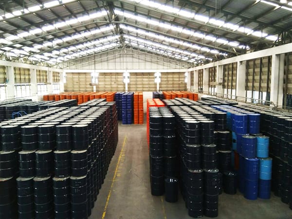 Palletized steel drums filled with industrial chemicals, ready for distribution.