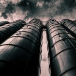 Low angle view of industrial silos with a dramatic cloudy sky in the background, emphasizing modern industry.